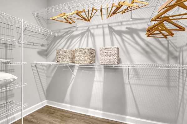 A room with a white wall and a shelf with baskets on it.
